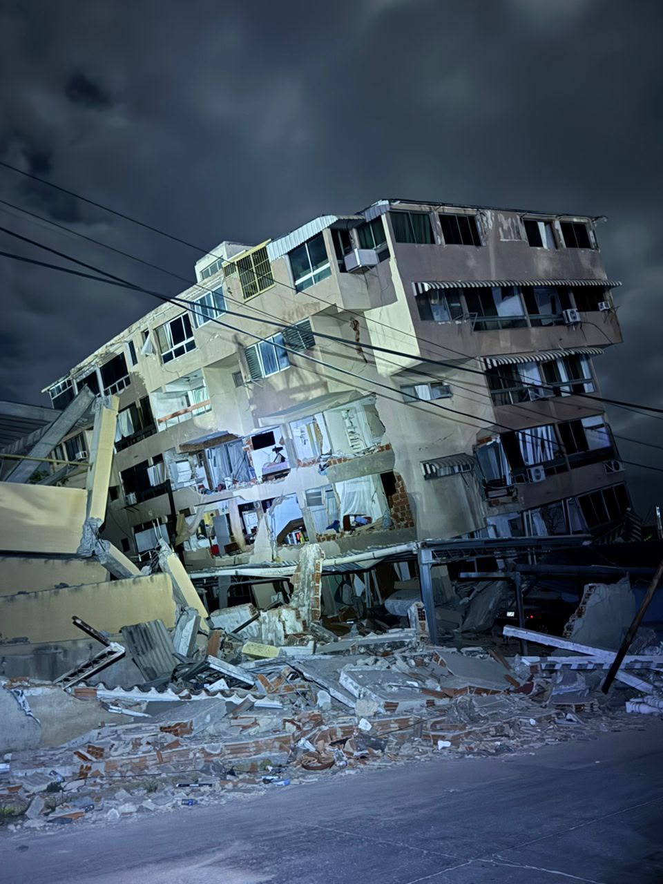 Severely damaged residential building leaning at night